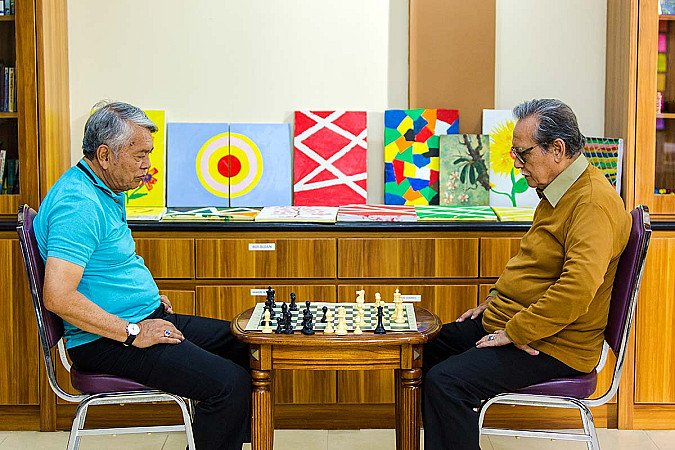 Two older adults playing chess to train focus and memory